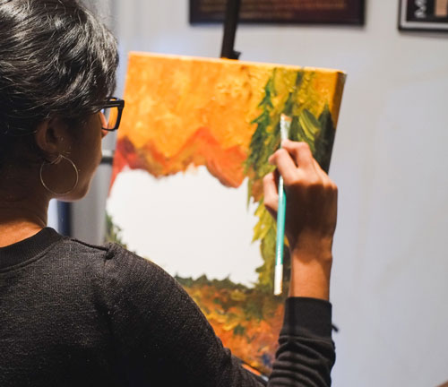 Girl holding a paintbrush and painting on a canvas