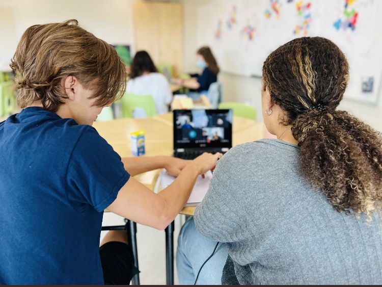 Two students work on their laptop together at a desk