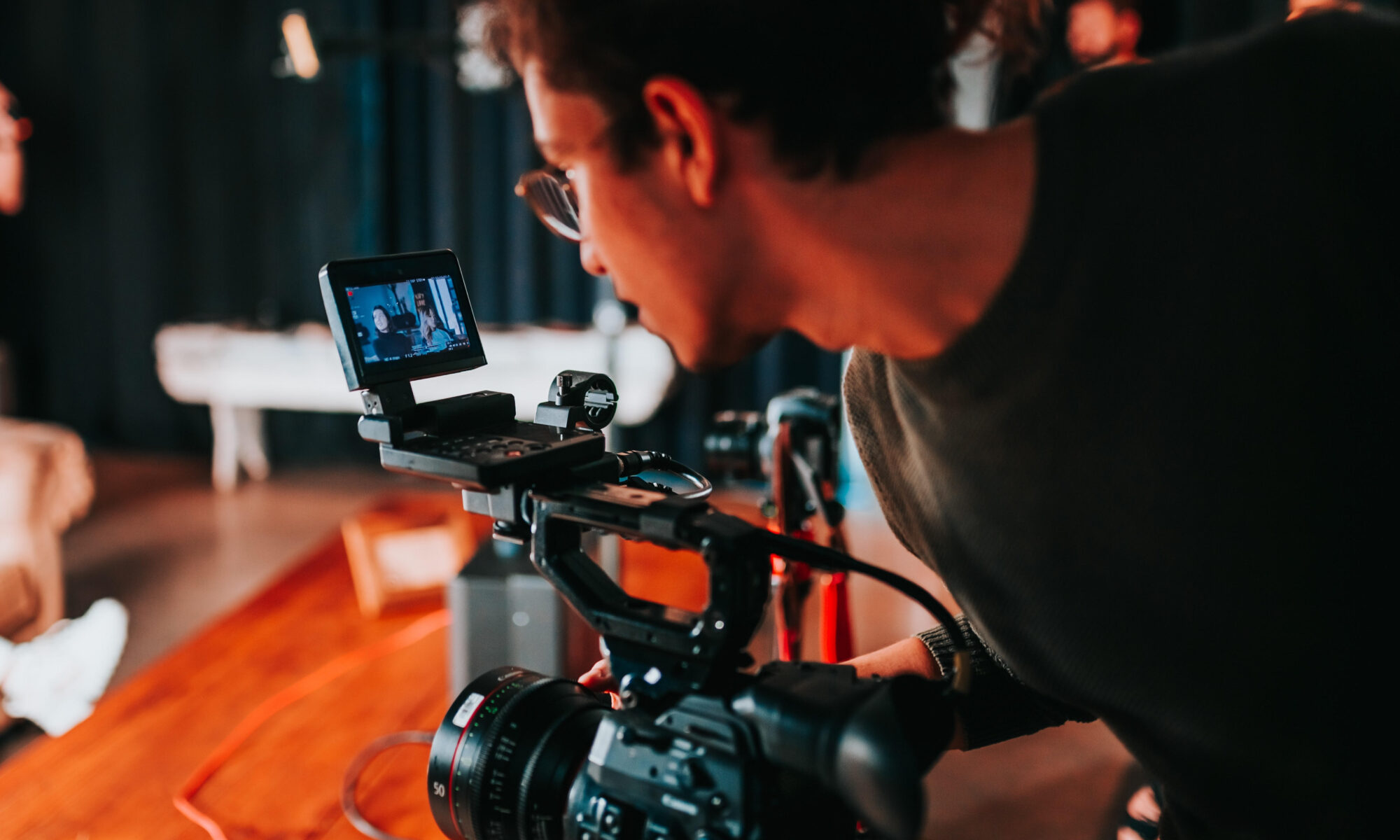 Filmmaker looks through the viewfinder on his camera as he films a scene